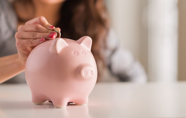 Jeune femme qui met de l'argent dans un petit cochon